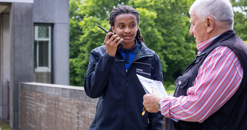 Student beveiliger helpt bezoeker bij gemeentehuis