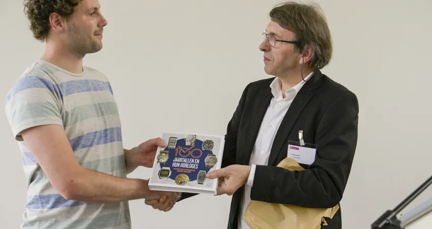Het boek 100 jaartallen en hun horloges overhandigd aan jongste docent Uurwerktechniek