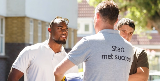 2 jonge mannelijke studenten Assistent Dienstverlening in een sportomgeving met bal staan tegenover elkaar