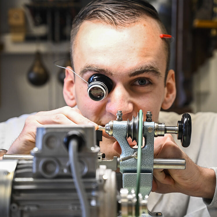 Student Uurwerktechnicus bekijkt een horloge door een oogloep
